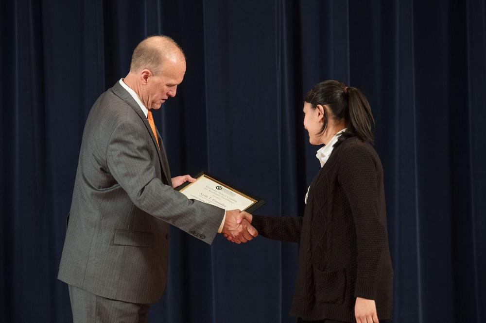 Doctor Potteiger shaking hands with an award recipient in a brown cardigan